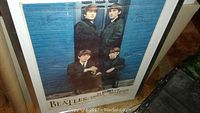 Framed Beatles London Palladium poster showing band members against a blue brick wall background.