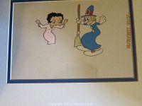 Photo of the framed animation cel showing Betty Boop in pink dress and a cartoon witch in blue dress holding a broom, matted and framed.