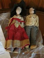 Photo of two vintage Mexican dolls, female with detached head and male with striped pants and embroidered shirt, lying on a surface