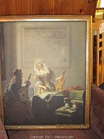 Centered view of the Vermeer-style framed painting showing a woman and man playing stringed instruments, with visible wear on the frame.