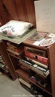Photo of stacked wooden bookshelf filled with assorted war books, WWII maps, Voice of Democracy shirt, and medals on top