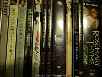 Photo showing DVD spine labels for several TV series including Outlander Season 1 (Volumes One and Two), Rosemary and Thyme Season 1, and others along with instructional DVDs.