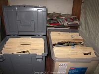 Two large plastic storage bins open to show many folders filled with postcards organized by various locations and states.