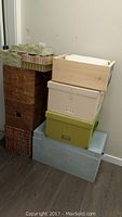 Stacked assortment of storage boxes and wicker baskets in various sizes, materials and colors including fabric, cardboard and wicker