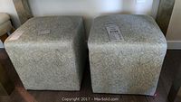 Two fabric cube stools placed side by side showing top and sides with light patterned upholstery.