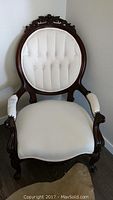 Front view of entire chair showing tufted oval back, seat and carved frame