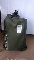 Green carrying bag with Light Speed branding, upright standing containing air mattress and accessories.