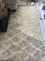 Ivory wool shag rug laid out on floor beneath sofa and furnishings
