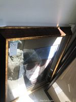Angled view of framed artwork showing portrait of man in hat under reflective glass