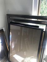 Several picture frames leaning against a wall in natural light, showing a range of sizes and styles.