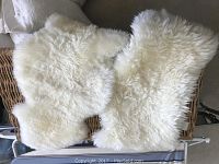 Two white IKEA RENS sheepskin rugs with fluffy texture placed on a basket.