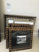 Five framed art prints resting on carpet against a wall, various wood style frames shown