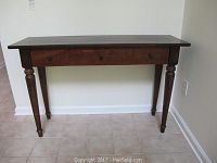 Front view of the wooden decorator's table showcasing its three drawers and turned legs.