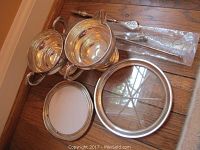 Overview of trays, cream and sugar bowls, and spoons arranged on wood floor.