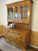 Front view of the wooden Cushman colonial dining hutch showing upper glass cabinets and lower drawers and doors.
