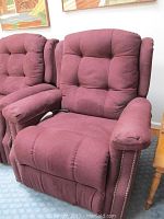 Photo of maroon upholstered lift chair showing tufted backrest, padded armrests, and nailhead trim along armrest sides.