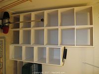 Two white wooden shoe racks with cubby compartments for shoe storage on floor against a wall.