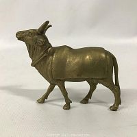 Side view of a 3 inch brass goat figurine on a white background