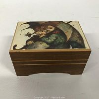 Closed view of the wooden music box showing the colorful lid illustration with two children holding an umbrella.