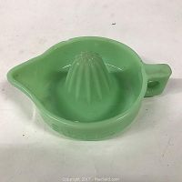 Green glass Sunkist juice reamer with handle and spout, made of jadeite glass.
