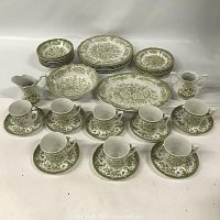 Full view of entire set showing cups on saucers, plates in stacks and two serving platters with creamer pitcher.