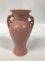 Front angled view showing pink coloration, cutout handles, and smooth finish on the vase.