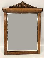 Front view of rectangular oak framed mirror with carved top decoration.