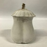 Front view of white ironstone sugar bowl with scalloped lid and metal knob.