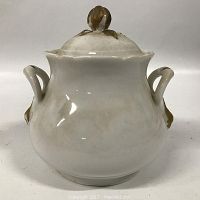 Side view of white ironstone container with matching lid showing two handles and brown decorative accents.