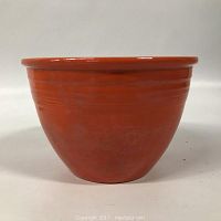 Front profile of an orange ceramic bowl showing glossy finish and horizontal band detail near rim