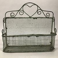 Front view of vintage wire basket with heart-shaped decorative detail and mesh basket body.