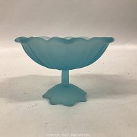 Frosted blue glass candy compote from a side angle, showing scalloped rim and flared form with petal-shaped base.
