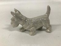 Side view of small porcelain Scottie dog figurine showing textured fur and raised tail.