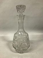 Clear cut and pressed glass decanter with stopper, standing 14 inches tall, detailed geometric patterns on body and stopper faceted design.
