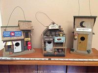 Three decorative bird houses side by side showing their distinct themes and size relative to a ruler