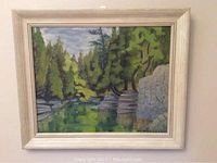 Frontal photo of the framed oil painting showing a forest river scene with greenery and rocks.