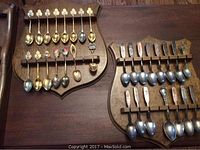 Photo of two wooden spoon racks holding multiple tea spoons including gold and silver toned spoons