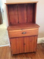 Front view of antique pine wash stand showing drawer with metal pull and two cabinet doors below, with a plank back panel shelf.
