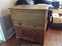 Front view of antique solid wood cabinet showing closed doors and drawer, natural wood finish with patina.