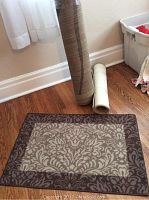 Small ornate floral medallion throw rug with a dark border and beige/brown center area