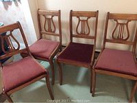 Four wooden harp back chairs grouped together showing overall condition and seating fabric.