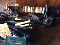 Wood lathe with wooden spindle mounted, chisels placed nearby, and woodturning book visible