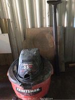Craftsman 5.5 HP wet/dry vacuum with red tank and black top, hose visible.