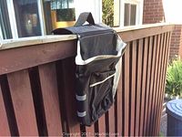 Side view of black bicycle saddle bag hanging on wooden railing, showing reflective strips and Velcro attachment.