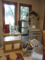 Overall kitchen storage items including baker rack, plastic drawers, wooden cabinet, glassware, and assorted accessories.