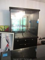 Front view of the large lacquered black hutch showing glass doors and shelving with bottom storage doors.