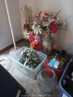 Full view of vases, glass baskets, and artificial flowers grouped on carpeted floor.