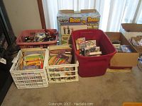 Photo showing multiple baskets and boxes containing children's books, VHS tapes, and the boxed modular dollhouse kits.