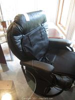 Front side of the black pleather swivel office chair with padded arms and headrest, showing the glider base
