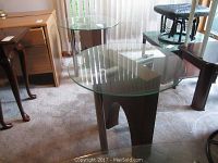 Three mid century modern glass top tables arranged on carpet with vertical blinds in background, showing coffee table and two end tables.